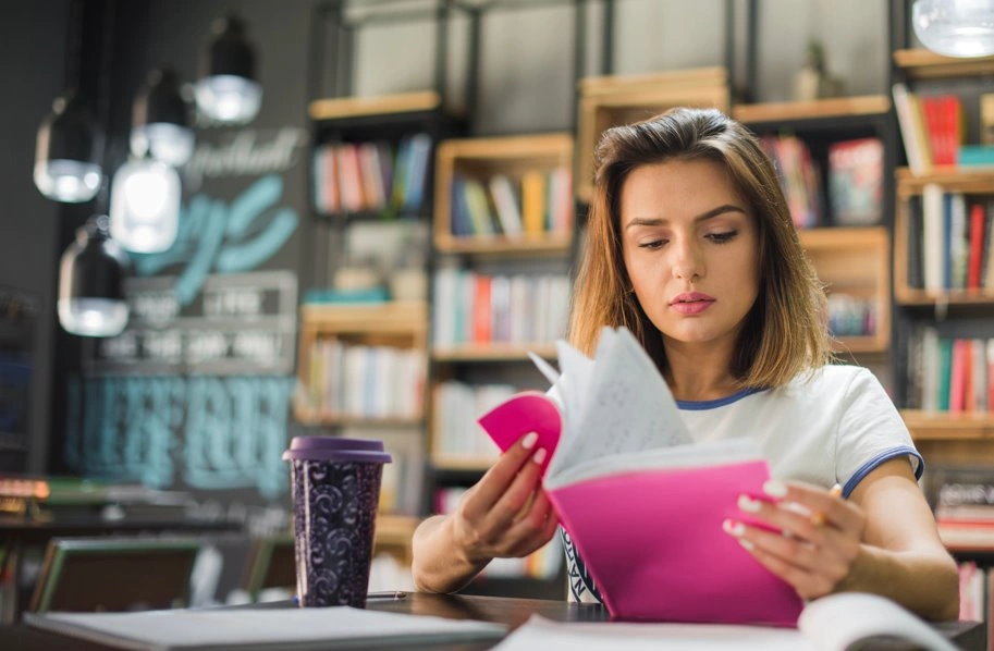 young woman reading notes in library study space